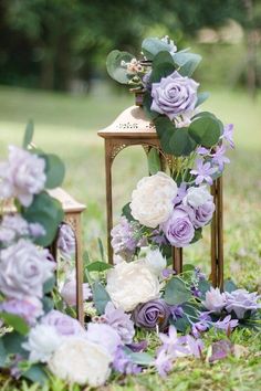 an arrangement of flowers and greenery on the ground near a light fixture in the grass