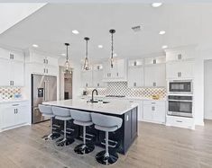 a large kitchen with white cabinets and an island