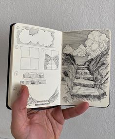 a hand holding an open sketch book with drawings on the pages and in front of it