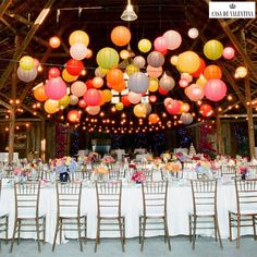 the tables are set up with paper lanterns hanging from the ceiling and chairs around them