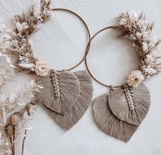 two hoop earrings with tassels and flowers on top of a white tablecloth