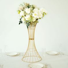 a vase filled with white flowers sitting on top of a table next to empty plates