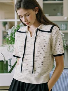 This product showcases a crochet-trimmed knit top, featuring a sophisticated contrast trim along the collar and front. The open-weave crochet design adds a unique textural element, while the short sleeves and lightweight fabric make it ideal for warmer weather or layering. Its relaxed fit allows for comfortable movement, creating an effortless, stylish look. - This top features a contrasting trim that frames the neckline and placket, providing a sharp, tailored edge.- The crochet pattern not only serves as an elegant detail but also ensures breathability and comfort.- Its short sleeve design is perfect for creating a polished look without the warmth of long sleeves.- The ribbed hem adds a cozy finish to the top, keeping it in place throughout the day. Beige Pointelle Knit Short Sleeve Top, Beige Short Sleeve Pointelle Knit Top, Casual Crochet Top With Lace Trim And Short Sleeves, Casual Short Sleeve Crochet Top With Lace Trim, Crochet Short Sleeve Knit Top For Spring, Spring Crochet Short Sleeve Knit Top, Chic Short Sleeve Crochet Top With Pointelle Knit, Short Sleeve Crochet Knit Top, Beige Short Sleeve Crochet Top With Crochet Trim