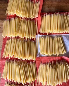 four red trays filled with uncooked pasta on top of a wooden table