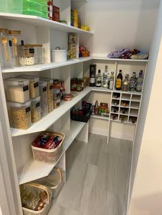 an organized pantry with white shelving and lots of food on the shelves in it