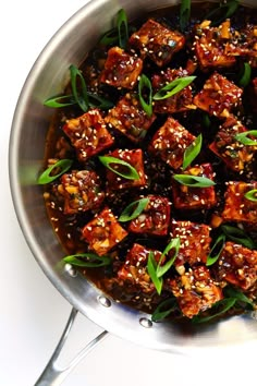 a pan filled with tofu covered in sauce and garnished with green leaves