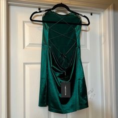 a green dress hanging on a door with a tag attached to the back of it