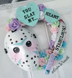 a white door with a mask and flowers on it that says you slay my heart