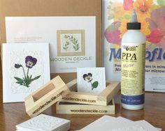 some crafting supplies are sitting on a table with flowers and cards in front of them