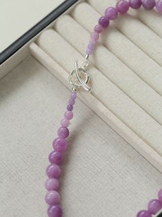 Embrace the essence of spring and summer with our Lavender Grapevine Gemstone Beaded Necklace! The enchanting purple hue exudes a blend of dreaminess and a hint of mystery. Crafted with romantic healing lavender gemstones delicately strung together, complemented by a minimalist OT clasp, this necklace embodies gentle elegance with a touch of individuality. Perfectly versatile, it effortlessly elevates any ensemble, whether paired with a solid-colored tee or a breezy resort sundress, exuding a charming Southern French allure. Metal: Recycled Sterling Silver Plated On Brass Gemstone: Natural Stone 10mm Length: 480mm Weight: 60g Lavender Gemstone Beaded Necklaces As Gift, Lavender Gemstone Beaded Necklaces For Gift, Lavender Gemstone Beads Necklace For Gift, Elegant Lavender Necklaces With Natural Stones, Handmade Lavender Crystal Necklaces With Round Beads, Lavender Faceted Beads Crystal Necklace Gift, Lavender Crystal Necklaces With Faceted Beads For Gifts, Elegant Lavender Necklaces With Gemstone Beads, Elegant Lavender Amethyst Crystal Necklaces