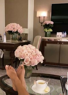 a woman's feet resting on a glass table with flowers in front of her