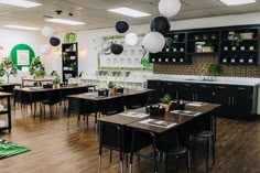 an empty restaurant with tables and chairs in front of the counter, potted plants hanging from the ceiling