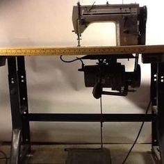 an old sewing machine sitting on top of a wooden table next to a measuring tape