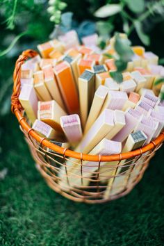 a basket filled with lots of different colored pieces of cheese on top of green grass