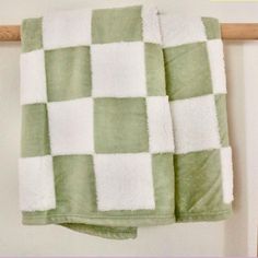 a green and white checkered towel hanging on a wall next to a wooden rail