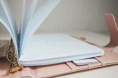 an open laptop computer sitting on top of a pink case next to a wallet and key