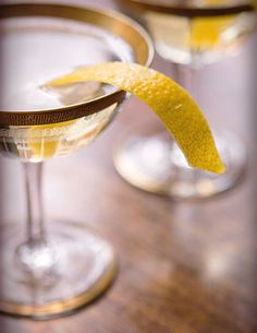 two martini glasses with lemon wedges in them