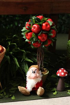 a gnome sitting next to a potted plant with apples on it