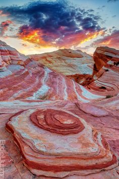 the sun is setting over colorful rock formations in the desert with swirls and curves