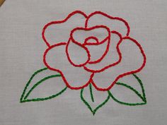 an embroidered rose on a white cloth with green and red stitching in the middle