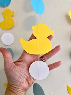 a hand is holding some paper cutouts in the shape of ducks