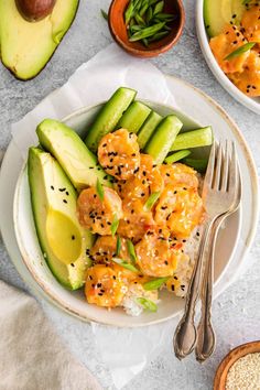 a white plate topped with shrimp and cucumber next to an avocado