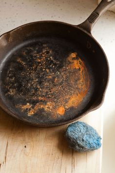 an old frying pan sitting on top of a wooden cutting board next to a rock