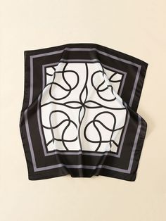 the black and white scarf is folded on top of the table with an abstract design