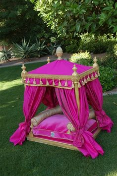 a pink canopy bed sitting on top of a lush green field