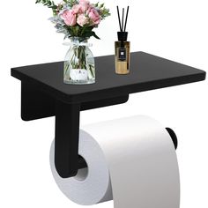 there is a vase with flowers on the table next to toilet paper and reeds