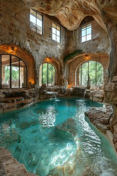 an indoor swimming pool in a large stone building with arched windows on the sides and water running through it