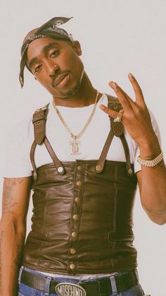 a man wearing a leather vest and hat making the peace sign