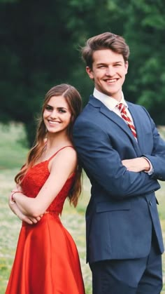 a man in a suit and tie standing next to a woman in a red dress