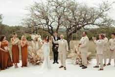 a group of people standing next to each other in front of a wedding arch with flowers