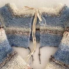 a blue and white knitted sweater with frayed edges