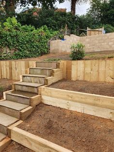 wooden steps leading up to the top of a garden area with dirt on the ground