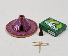 a candle holder next to matches and a box of coconut toothpaste on a white surface