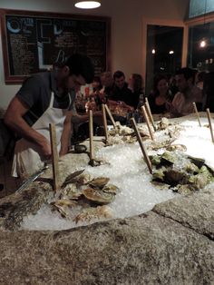 a group of people standing around a table with oysters on it