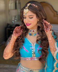 a woman in a blue outfit with jewelry on her head and hands behind her head