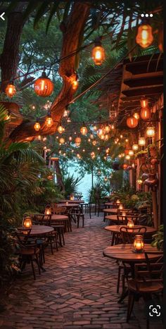 an outdoor dining area with lanterns hanging from the ceiling and tables set up for dinner