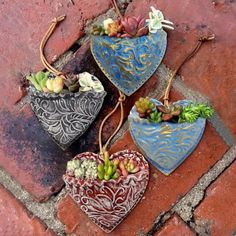 three heart shaped planters sitting on top of a brick floor