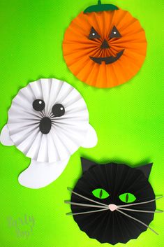 three paper pumpkins and a black cat with green eyes