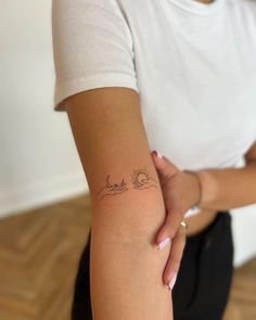 a woman with a tattoo on her arm holding onto another person's arm, both arms behind her back