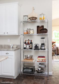 a kitchen with white cabinets and shelves filled with food