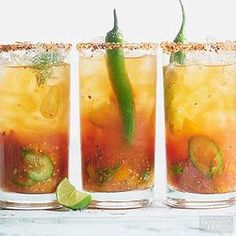 three glasses filled with different types of drinks and garnished with green peppers, cucumbers, and limes