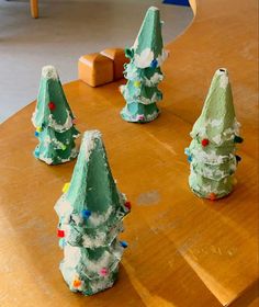 small green trees sitting on top of a wooden table covered in frosted icing