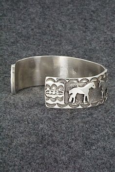 This sterling silver bracelet featuring horses was made by Navajo silversmith Preston Kinsel. The back is signed K and stamped sterling.Size: 5 5/8" (will fit up to a 6 7/8" wrist)Gap: 1 1/4"Width: 3/4"Free shipping on all orders! We ship with USPS and always include tracking. All orders ship within a day of payment.Returns are accepted up to 30 days after you receive your order. Just send us a message. Our shop offers cash back or store credit. The item must be returned in new condition. Adjustable Sterling Silver Horse Design Jewelry, Western Sterling Silver Cuff Bracelet Gift, Adjustable Western Sterling Silver Bracelet For Gift, Western Sterling Silver Bracelets, Adjustable Sterling Silver Western Cuff Bracelet, Western Style Sterling Silver Bangle, Adjustable Western Sterling Silver Cuff Bracelet, Western Style Sterling Silver Bracelets, Western Style Engraved Bracelets For Gifts