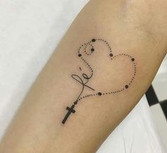 a cross and heart tattoo on the left arm, with dots in the shape of a line