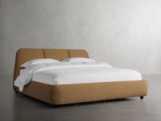 a bed that is made up with white sheets and pillows on top of the headboard