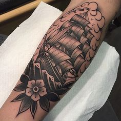 a man's arm with a ship tattoo on it